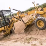 CAT 140 GC Motor Grader with moldboard raised to cut a bank slope