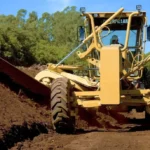 CAT 160K Motor Grader moldboard cutting a soil embankment