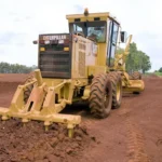 CAT 160K Motor Grader with rear ripper/scarifier on a red-soil site