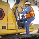 Operator climbing onto the CAT 320 track to enter the cab