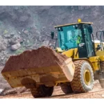 CAT 950 GC Wheel Loader carrying a full bucket of soil at a quarry