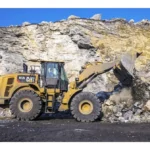 CAT 972L Wheel Loader digging blasted rock at a quarry face