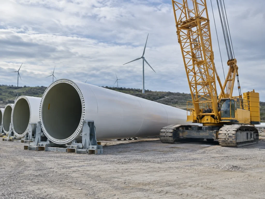 Componentes de una turbina eólica apilados junto a una grúa sobre orugas